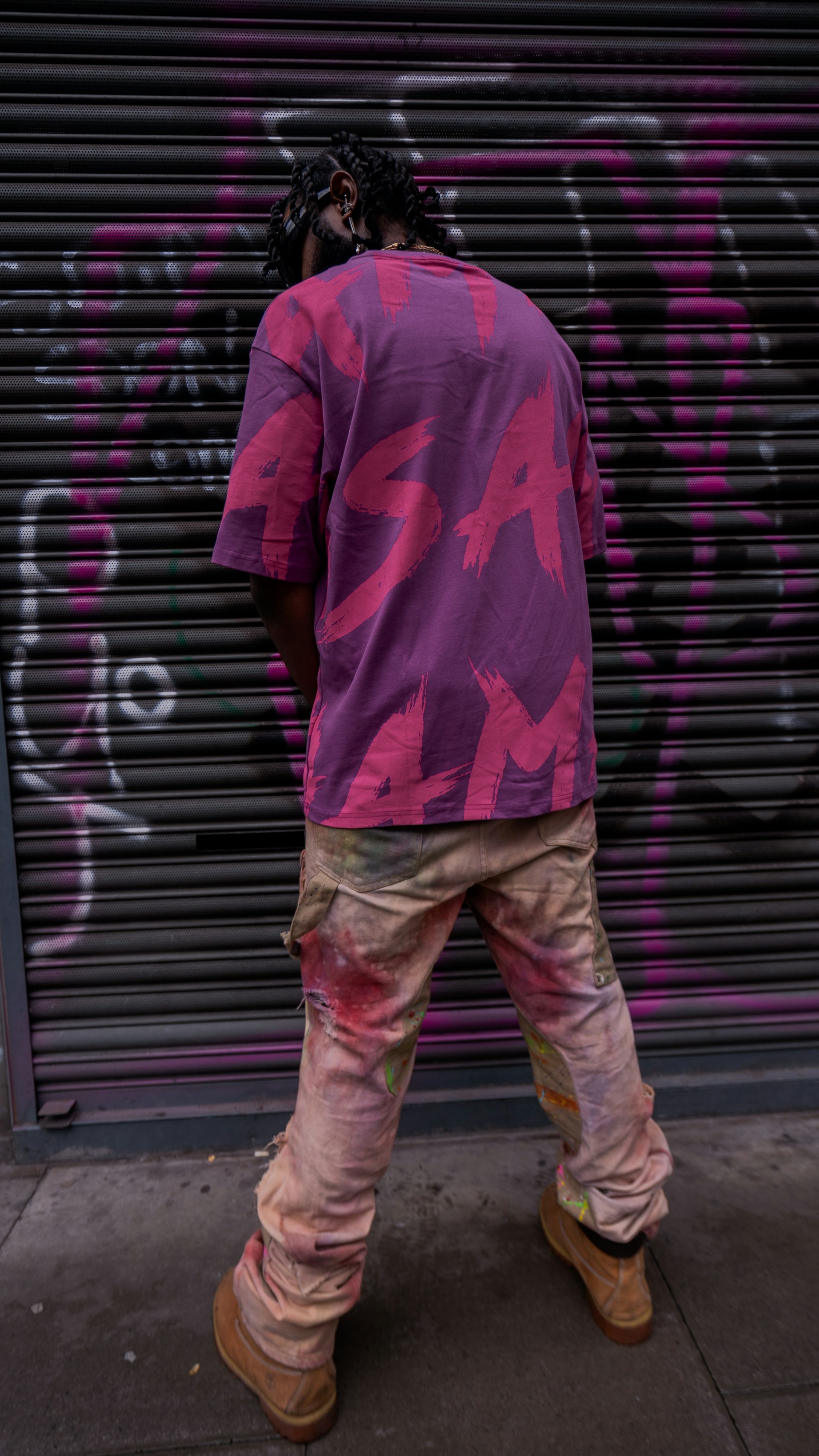 a man standing in front of a graffiti covered garage door