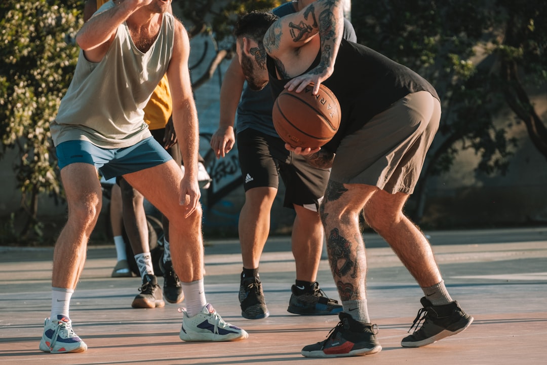 a group of young men playing a game of basketball, Intense street basketball action with players in athletic wear focuse