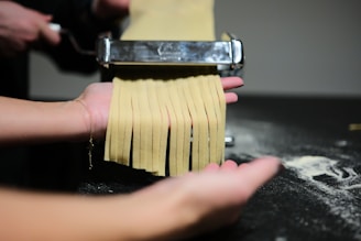 a person holding a pasta cutter over a pile of uncooked pasta