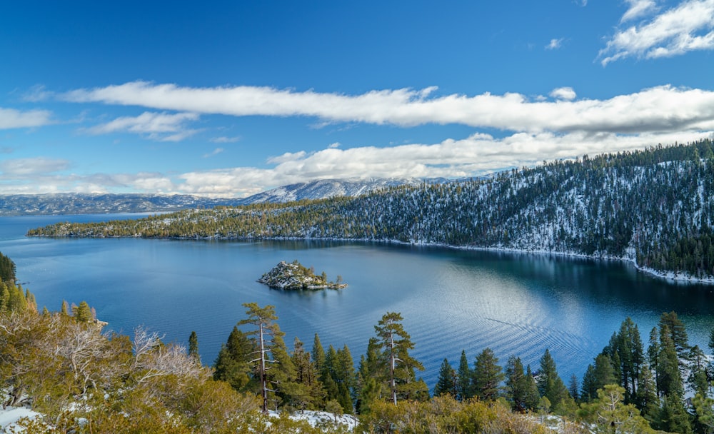 Ein See, umgeben von Bäumen und Bergen unter blauem Himmel