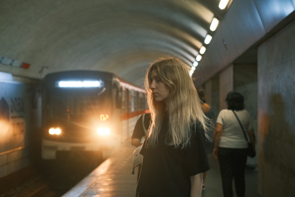 a woman standing in a subway station next to a train