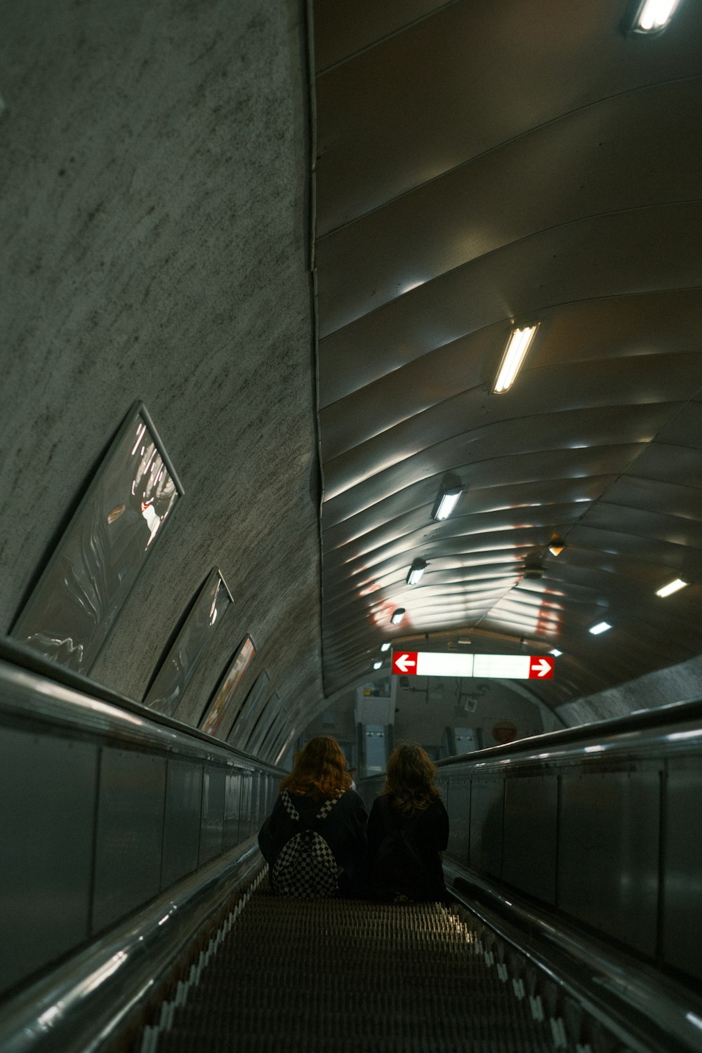 two women sitting on an escalator in a building