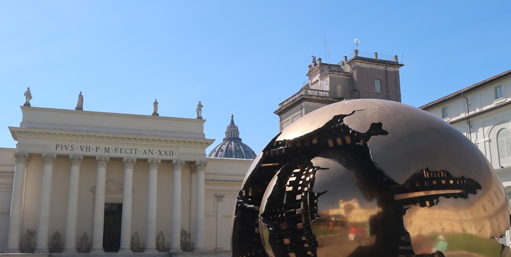 a large metal ball sitting in front of a building