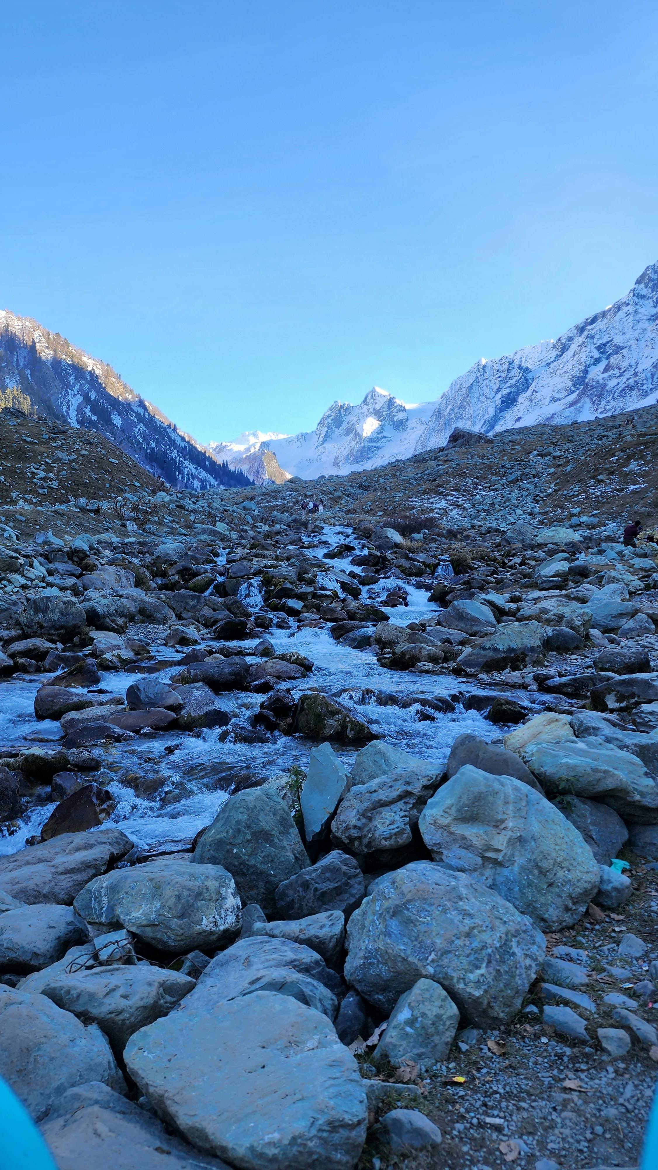 a rocky river running through a valley with mountains in the background