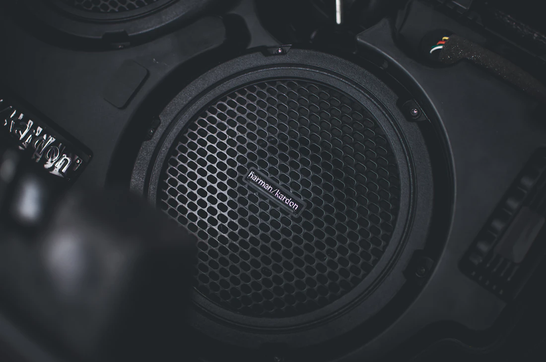 A subwoofer with a mesh grille filling the frame in a dark car enclosure