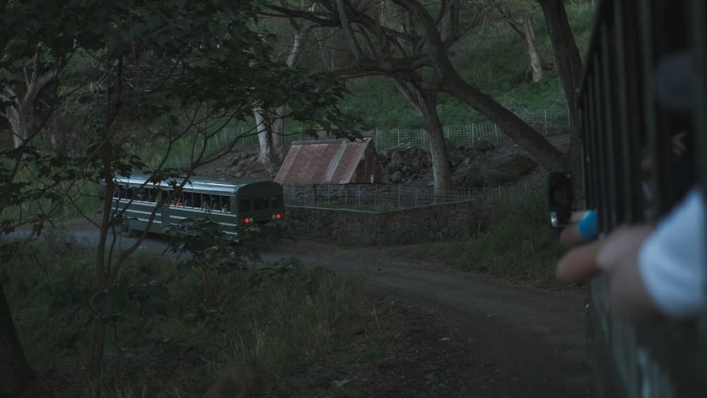 a bus driving down a dirt road next to a forest