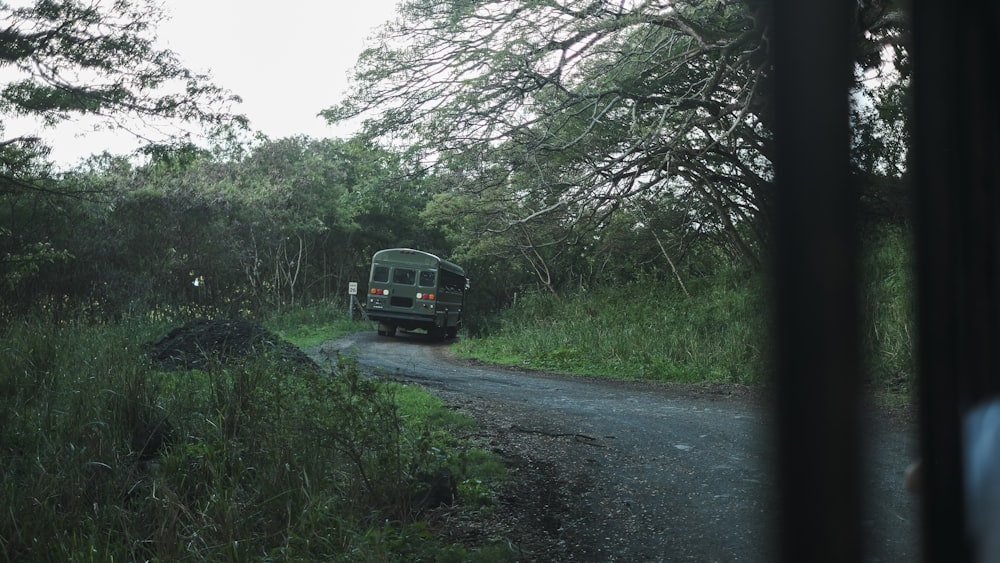 a truck driving down a dirt road next to a lush green forest