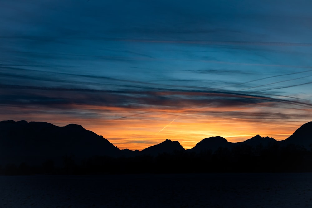 a sunset with mountains in the background