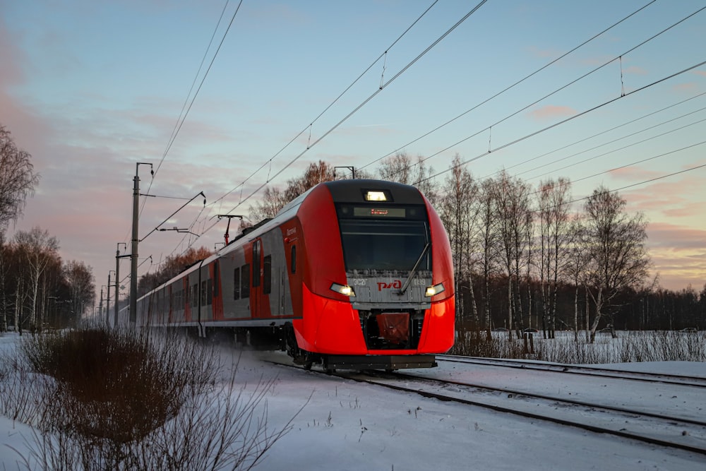 a red train traveling down train tracks next to a forest