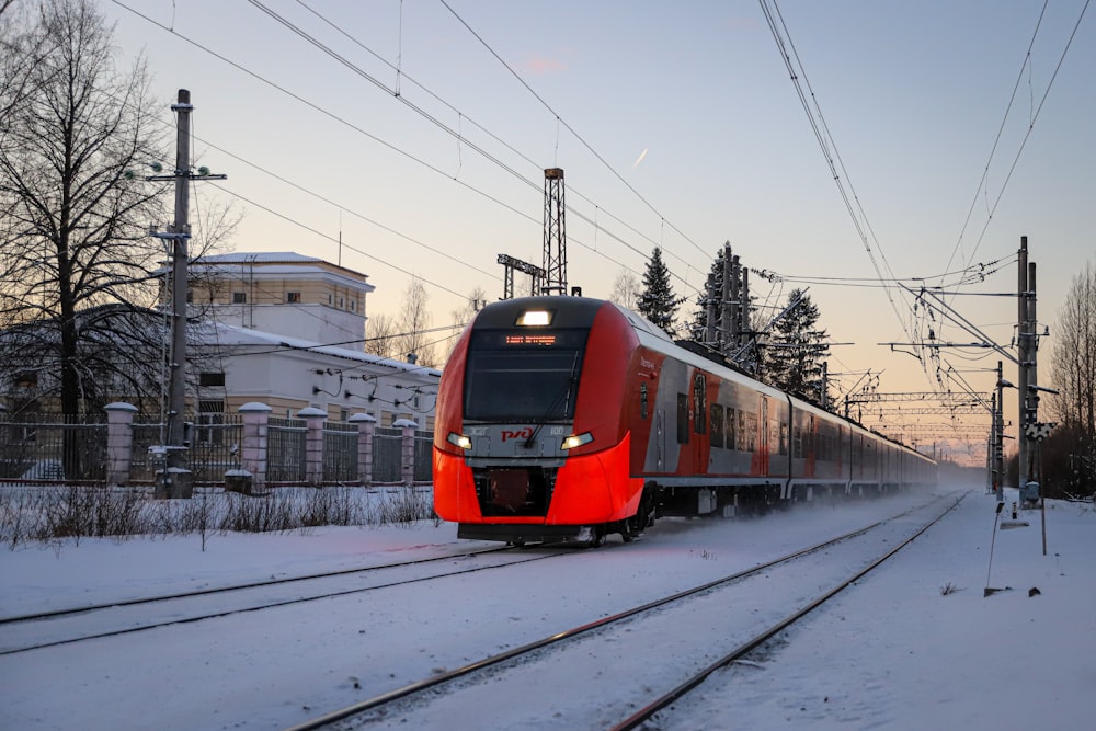 a red train traveling down train tracks next to a building