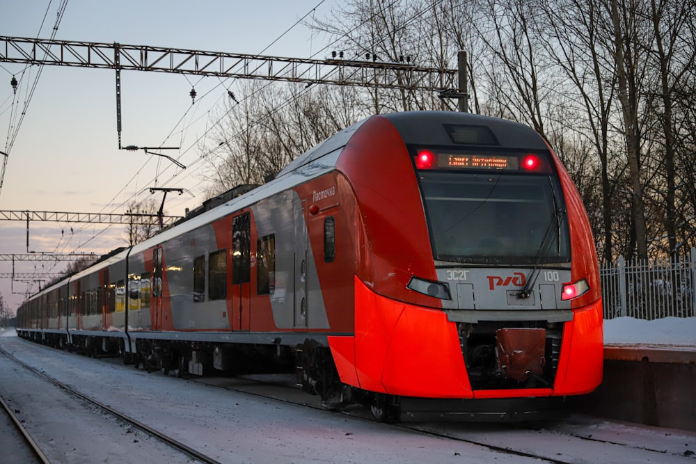 a red and silver train traveling down train tracks