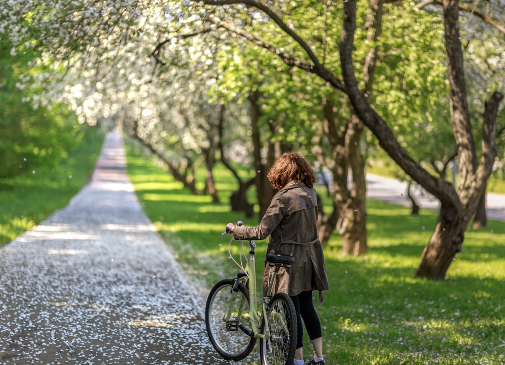 a woman standing next to a bike in a park