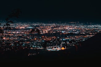 a view of a city at night from a hill