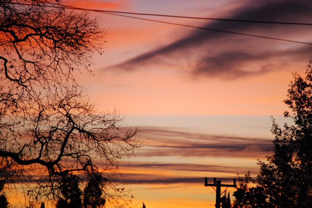 a sunset with clouds and a telephone pole in the foreground