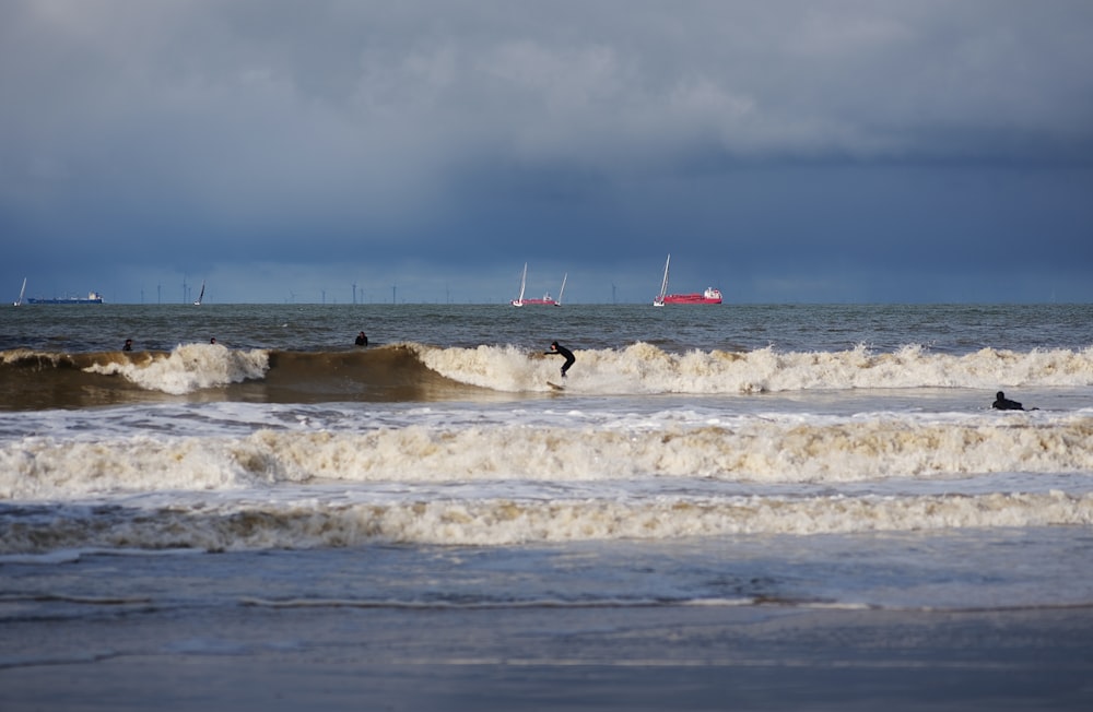 a group of people riding surfboards on top of a wave