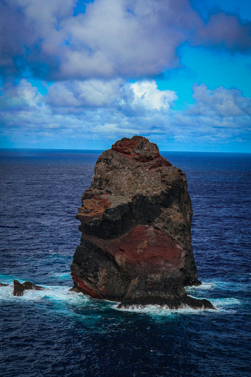 a large rock sticking out of the middle of the ocean