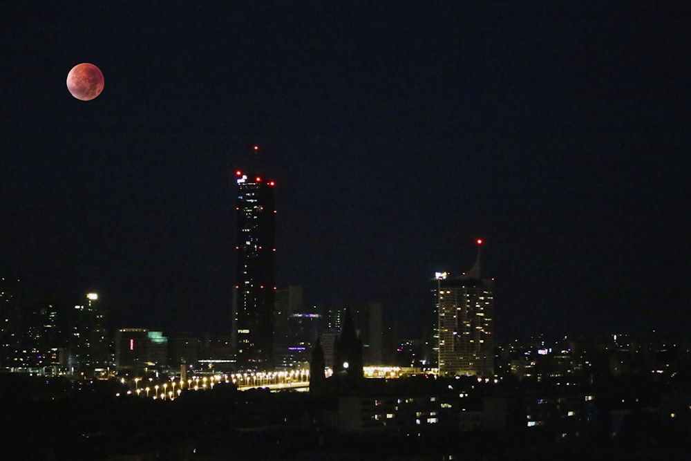 a full moon is seen over a city at night