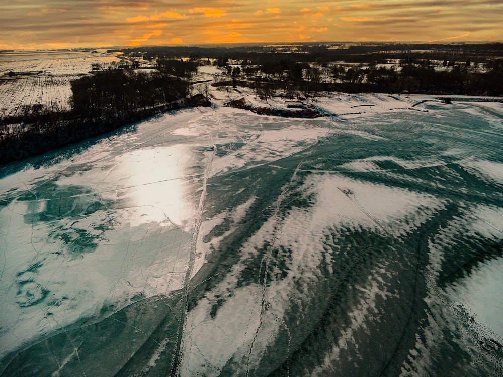 an aerial view of a frozen river at sunset