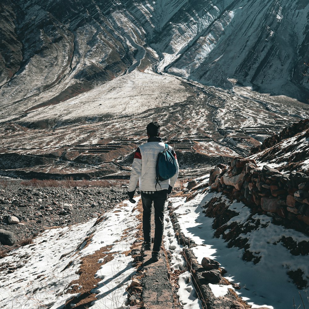 a man with a backpack walking up a snow covered path