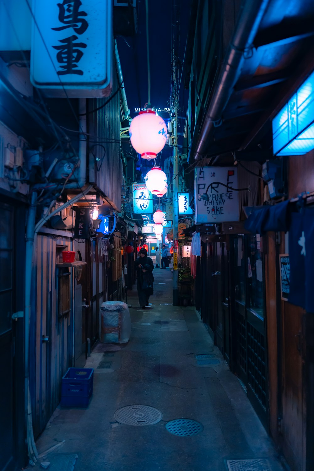 a narrow alley way with neon signs hanging from the ceiling