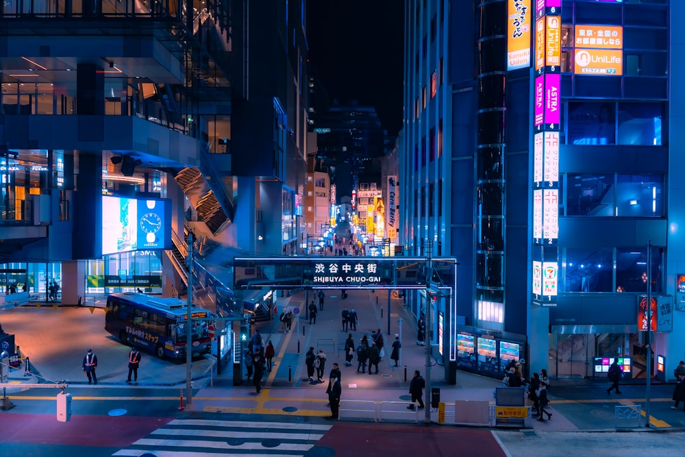 a busy city street at night with people crossing the street