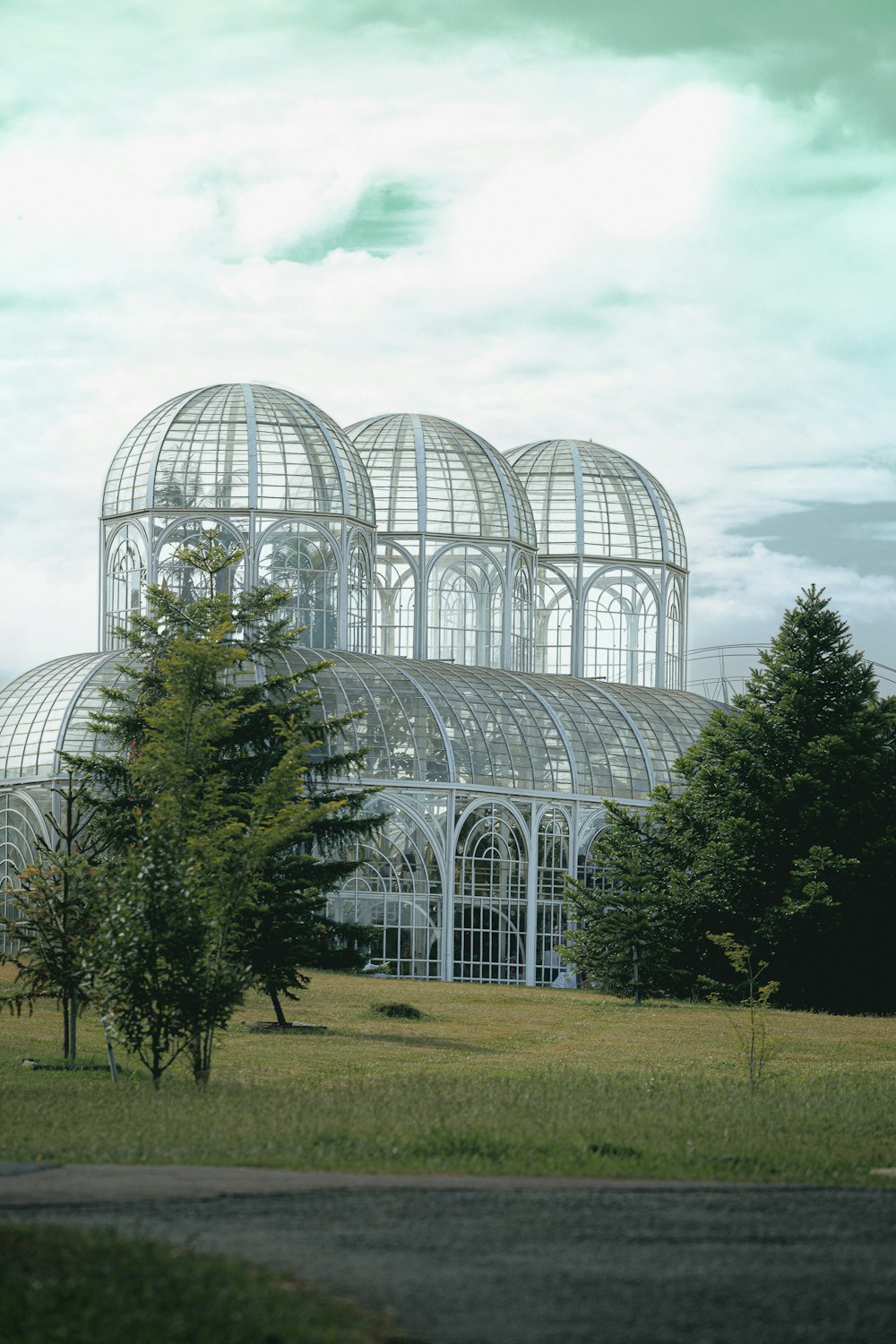 a large glass building sitting in the middle of a lush green field