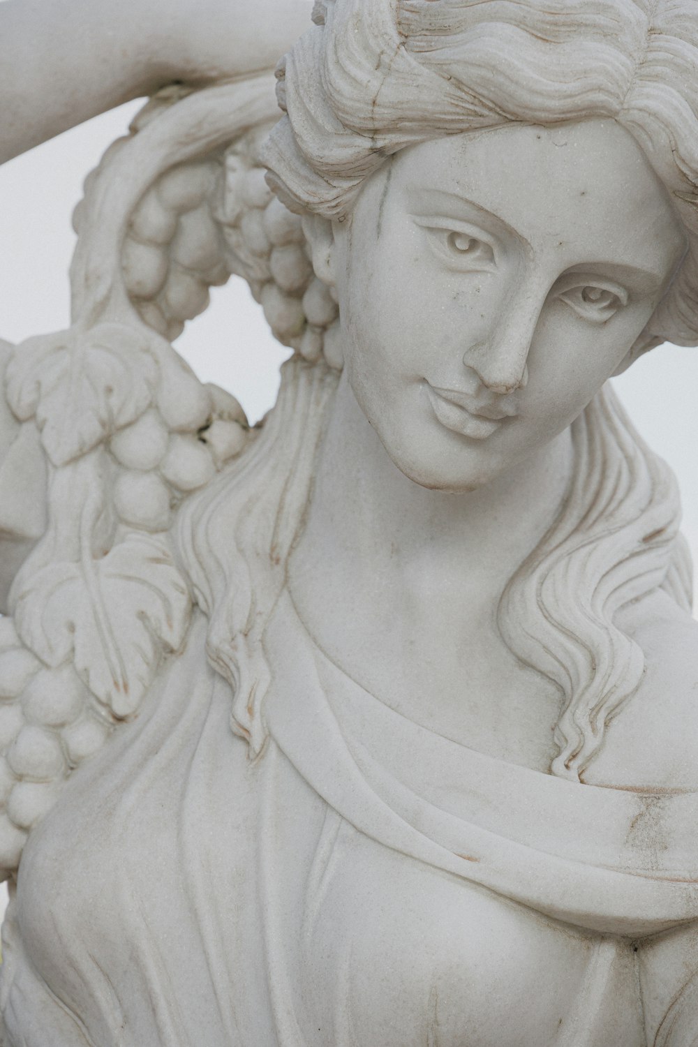 um close up de uma estátua de uma mulher segurando uvas