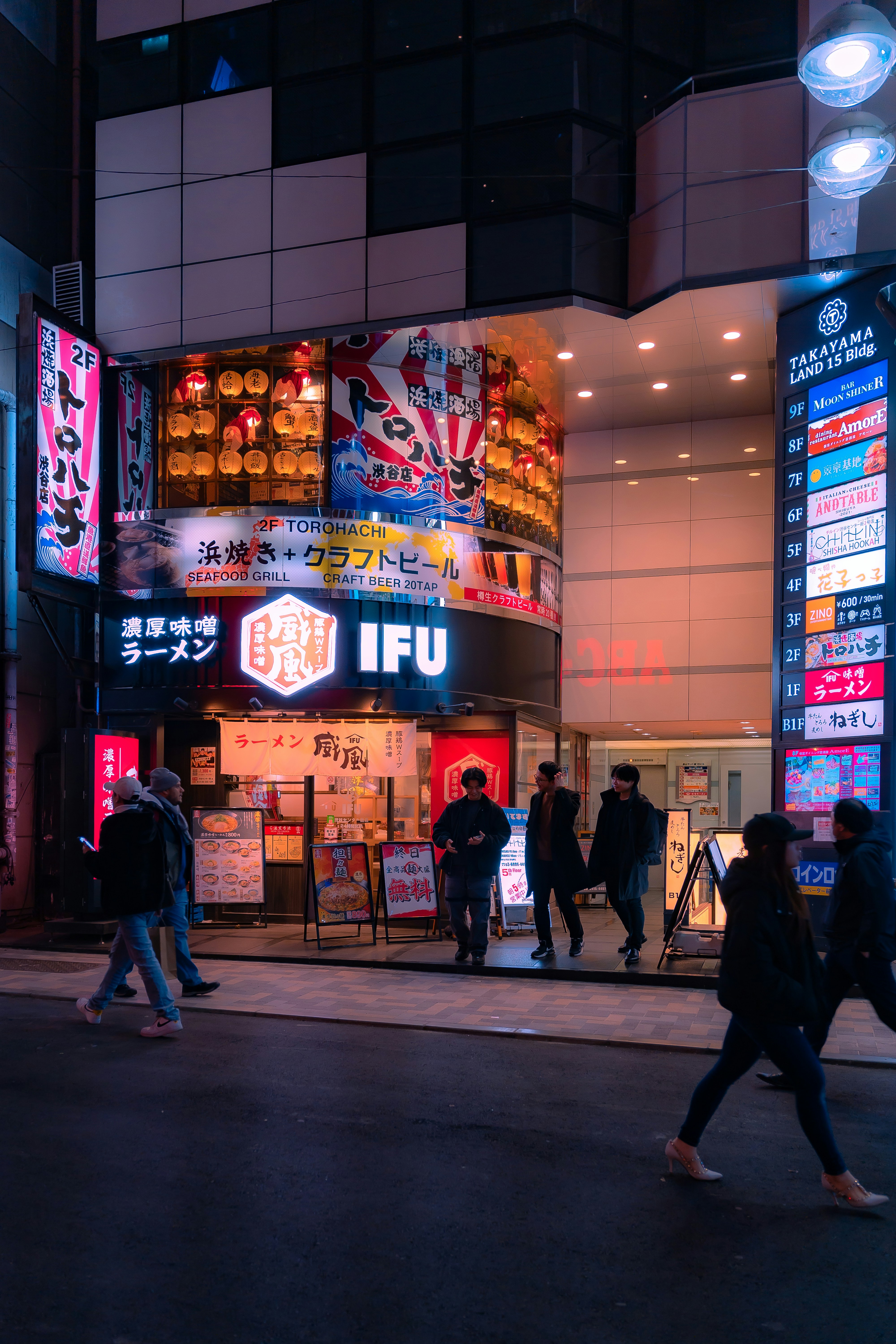 a group of people walking down a street at night