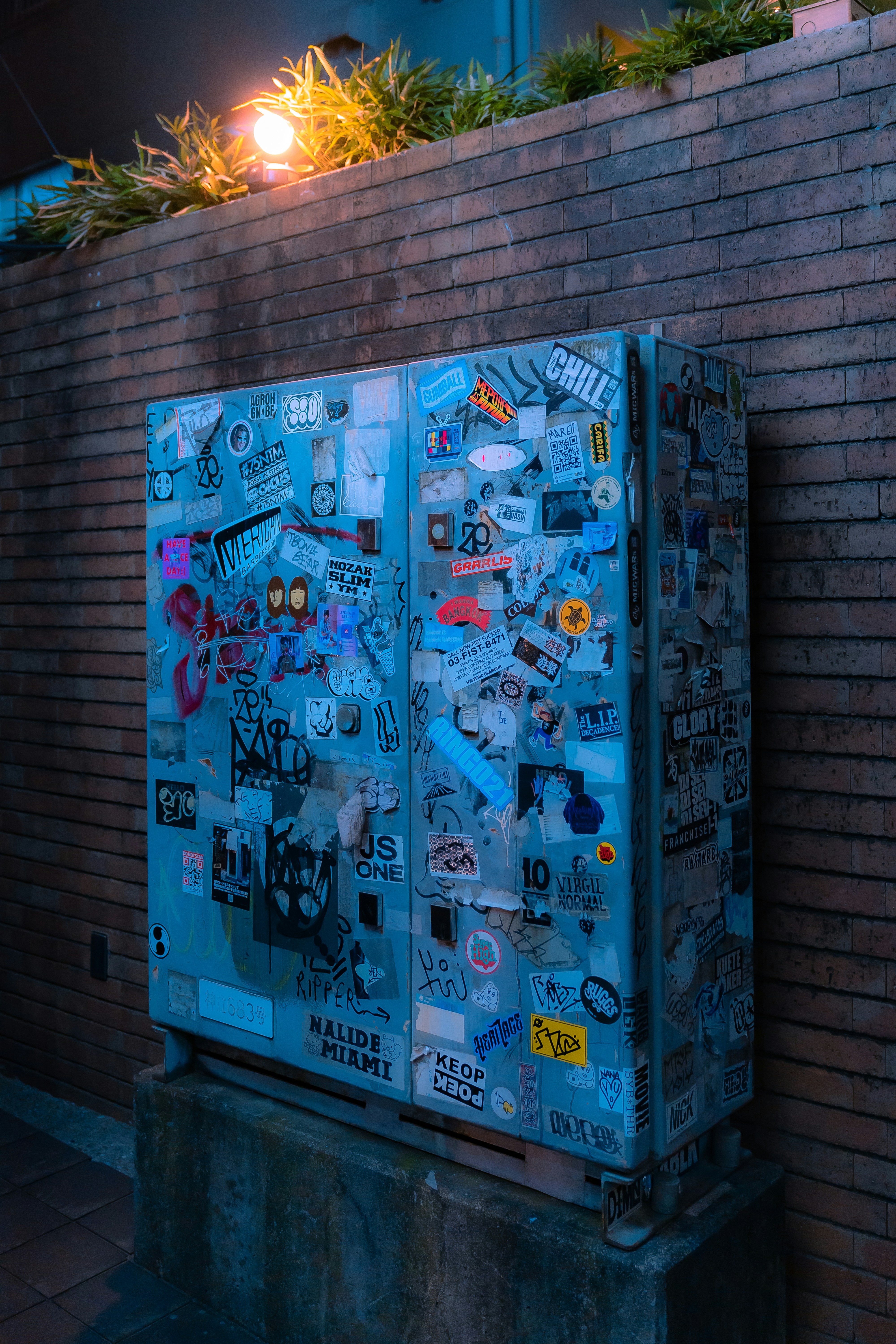 A metal box covered in stickers on a brick wall photo – Free Tokyo ...