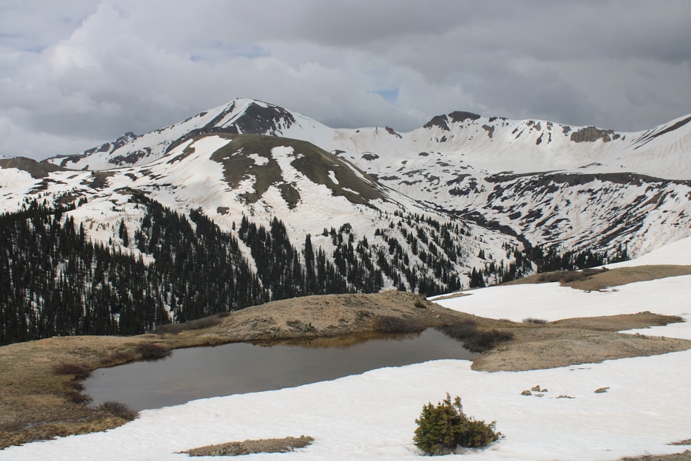 a snow covered mountain range with a lake in the foreground