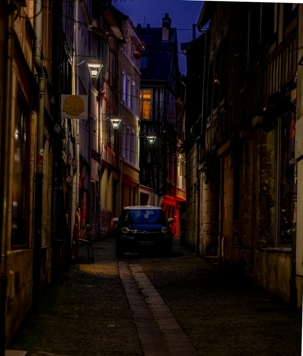 a car is parked on a narrow street at night