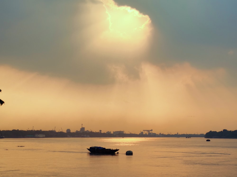 a boat floating on top of a lake under a cloudy sky