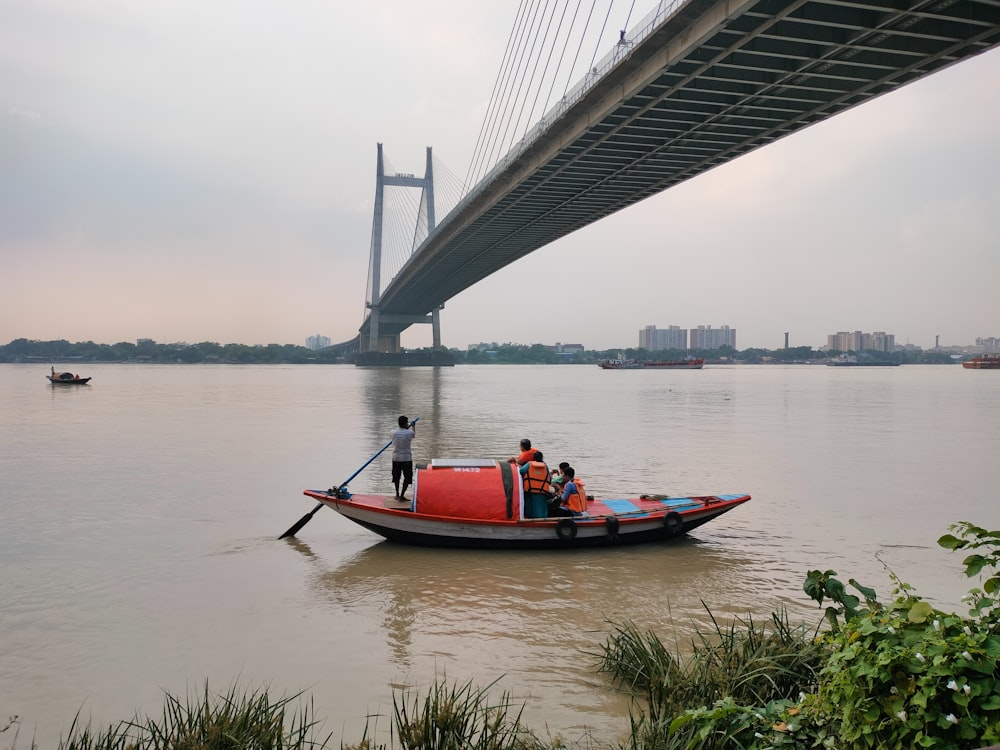 a boat with two people in it floating under a bridge