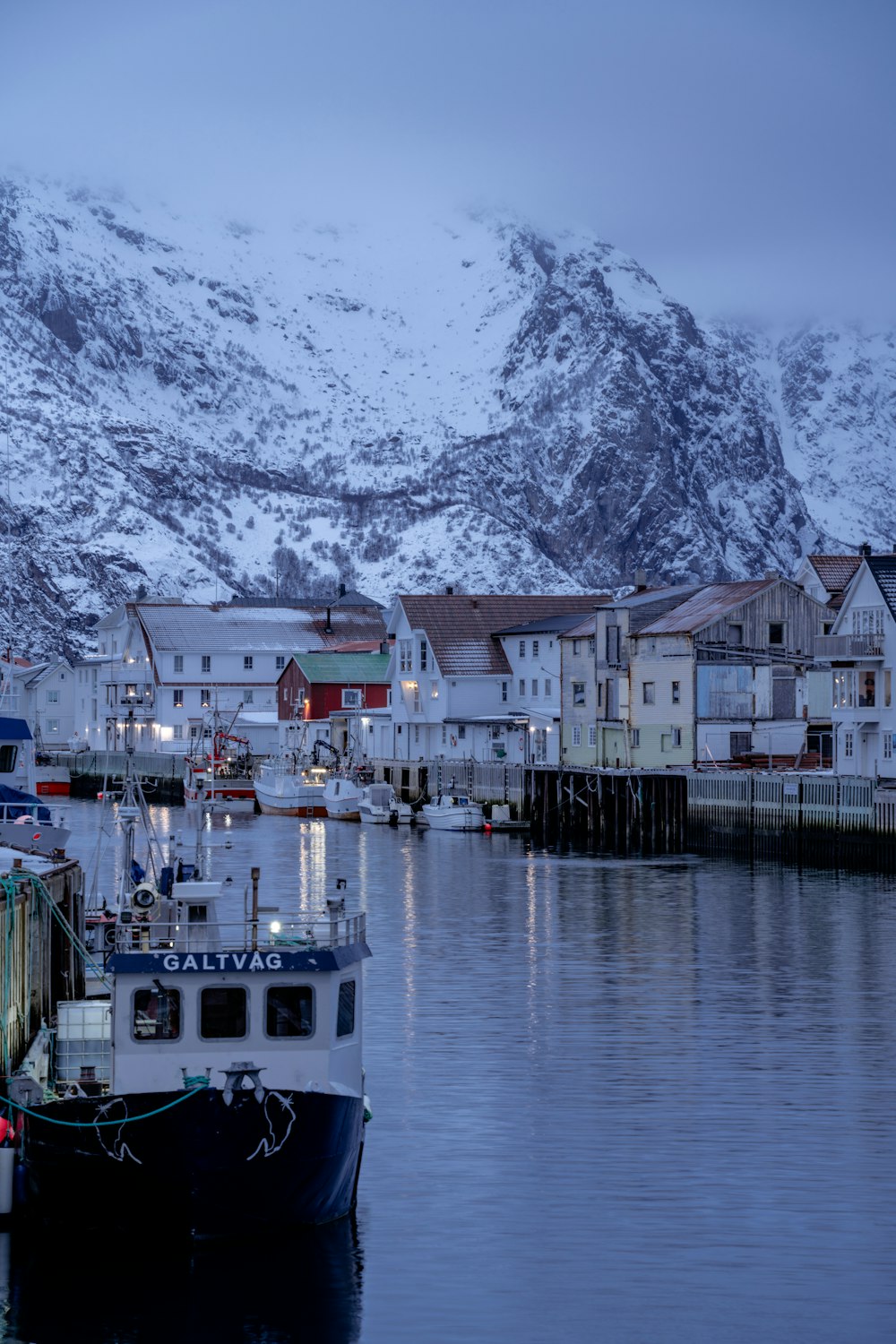 a boat is docked in a harbor with a snowy mountain in the background