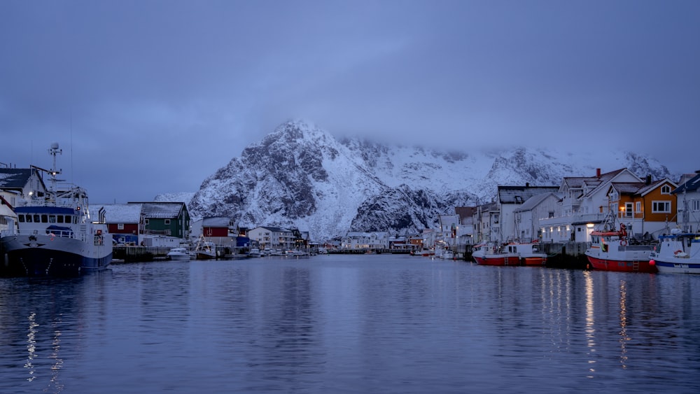 雪に覆われた山の隣の港に座るボートのグループ