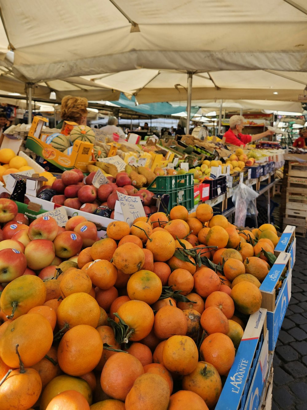 a fruit stand with oranges and apples for sale