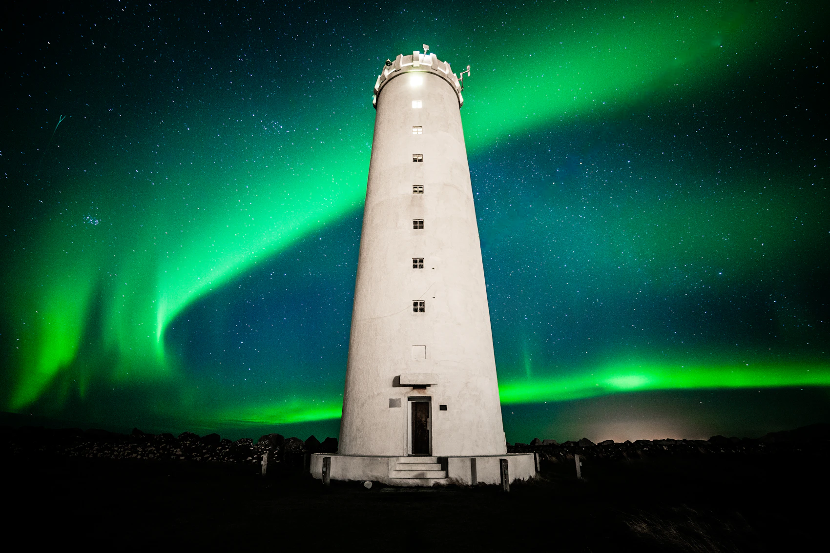 Green northern lights sweeping behind Grótta lighthouse near Reykjavík