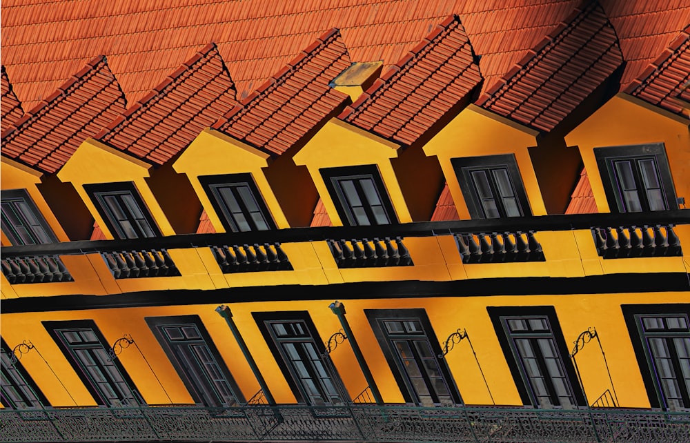 a yellow building with black windows and balconies