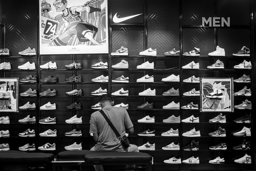 a man sitting on a bench in front of a display of shoes