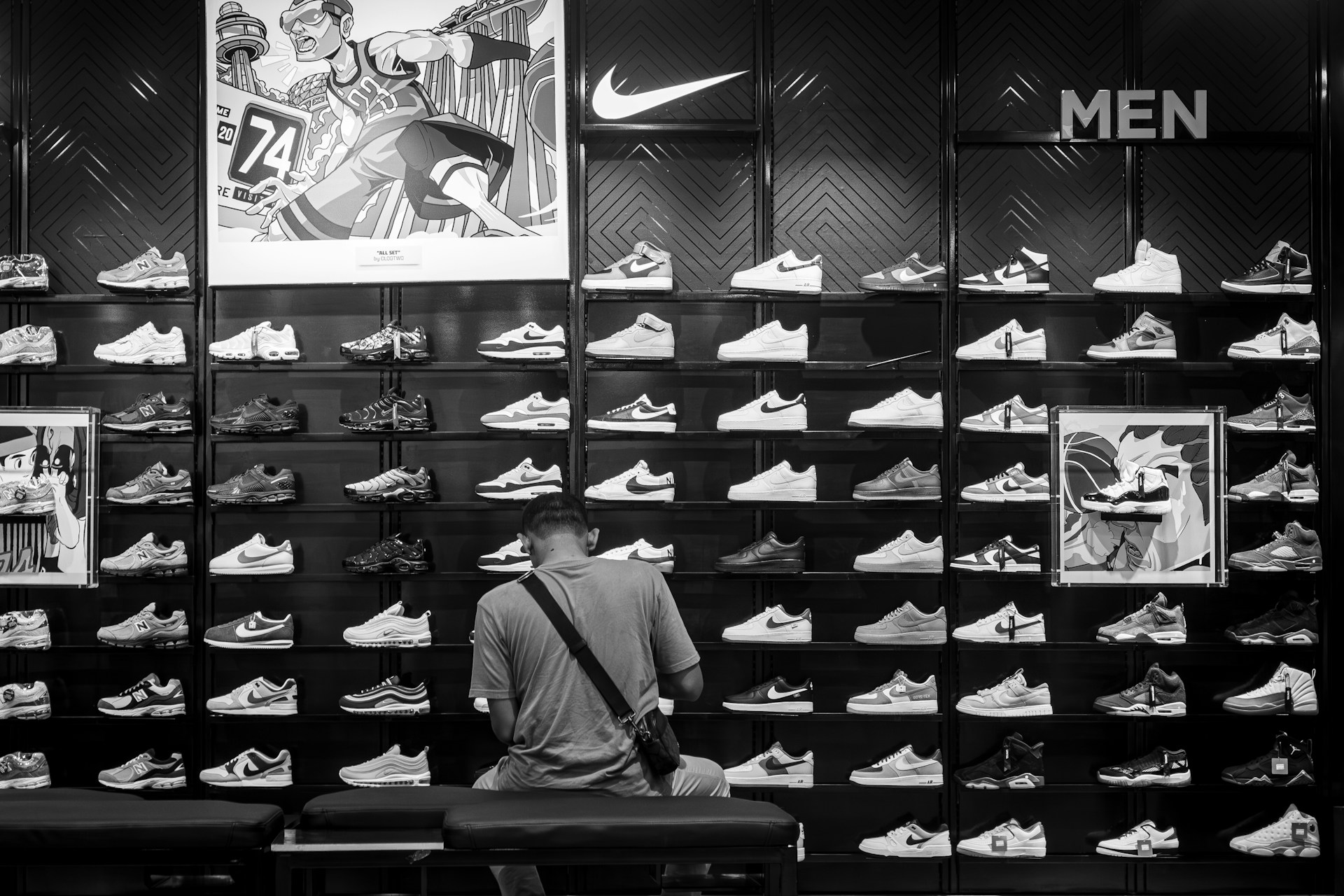 a man sitting on a bench in front of a display of shoes