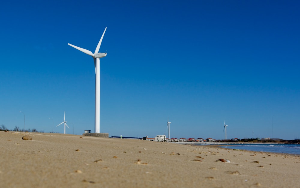 a wind turbine on a sandy beach next to a body of water