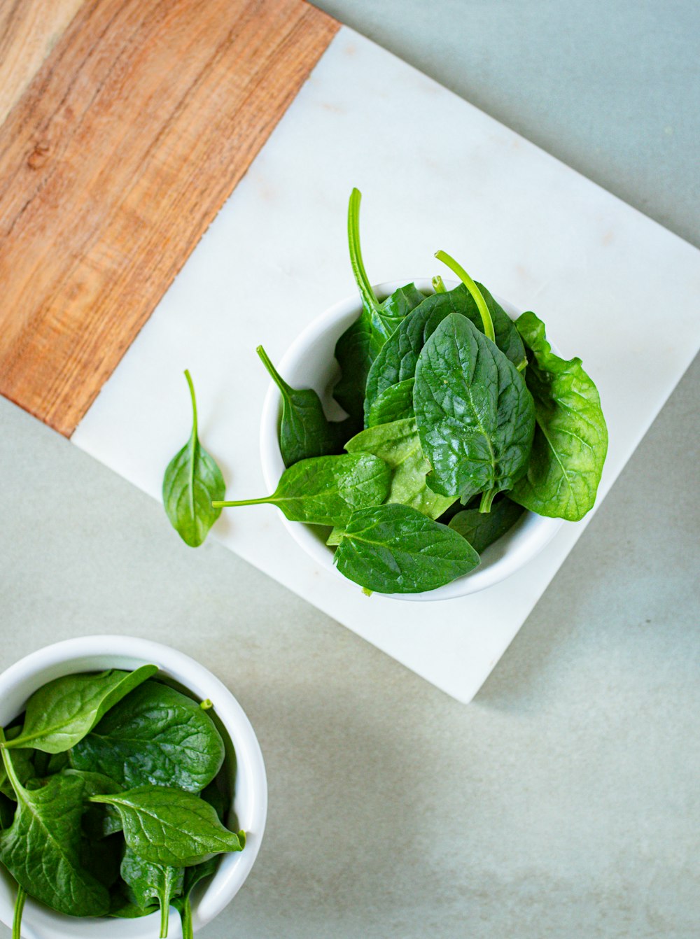 a couple of white bowls filled with green leaves