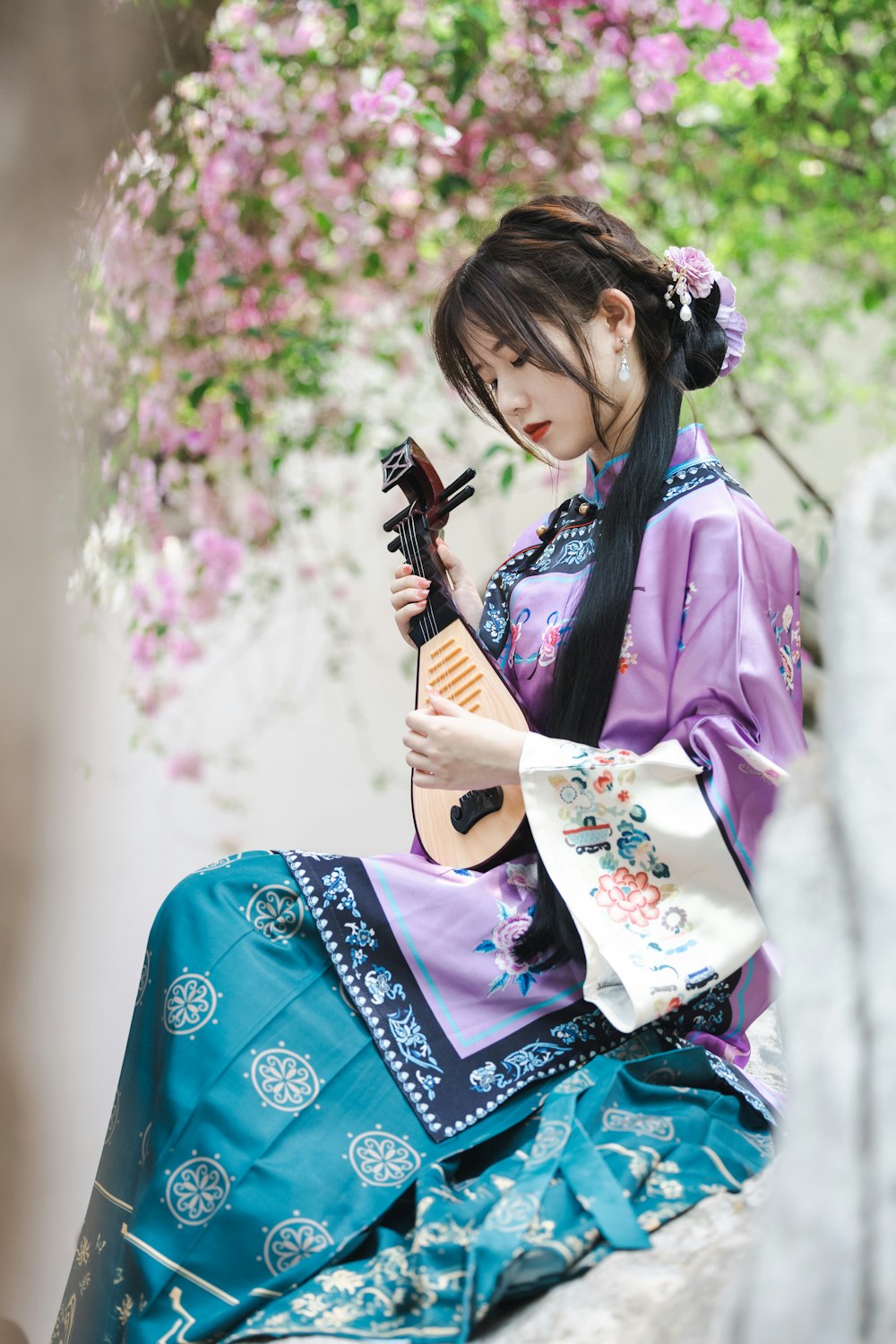 a woman sitting on a rock holding a guitar