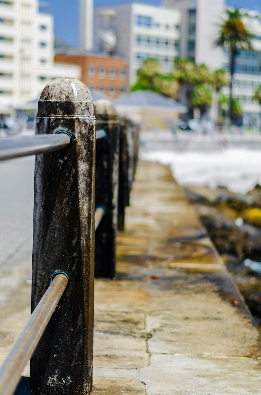 a metal fence next to the ocean with buildings in the background