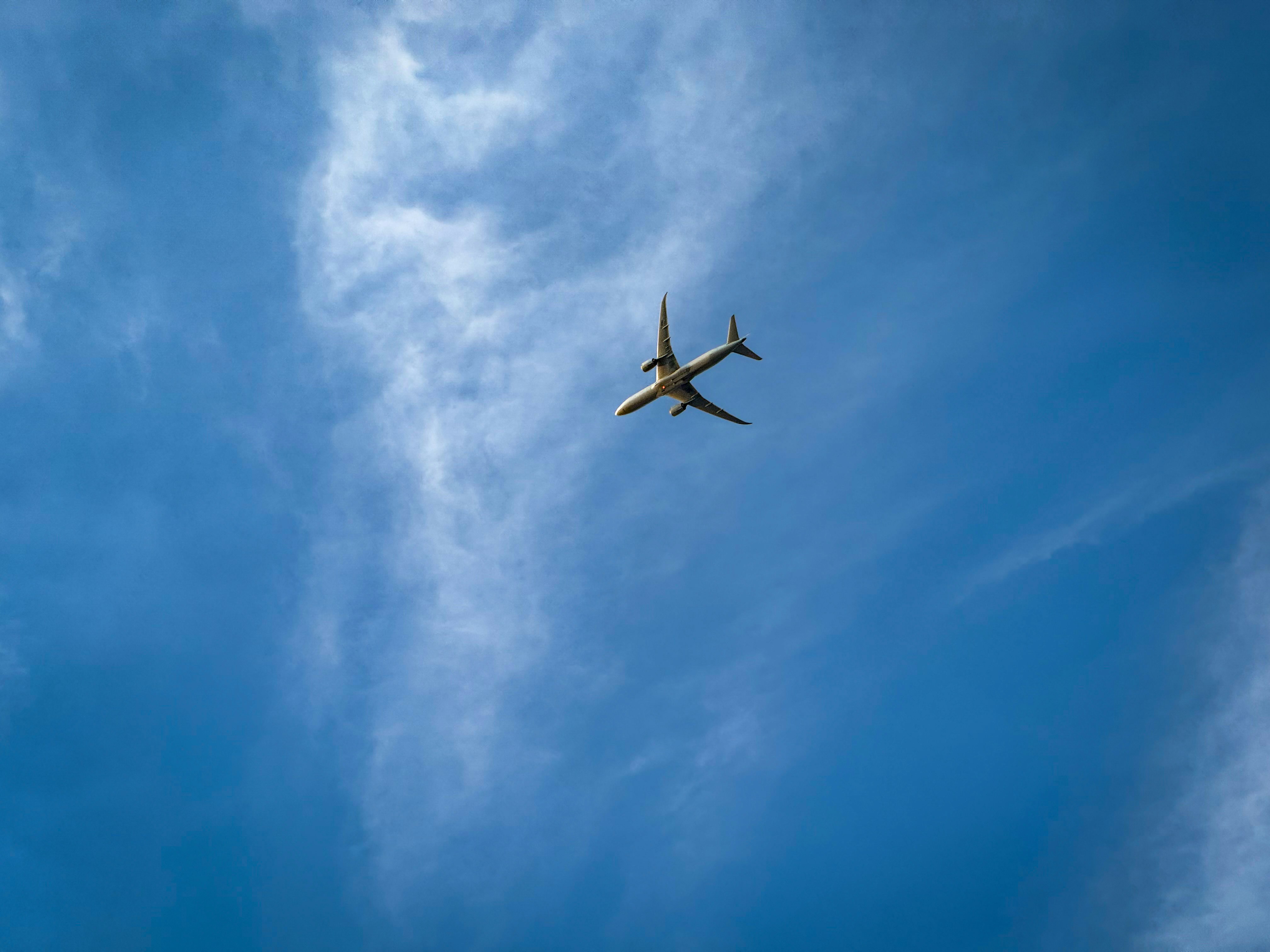 an airplane is flying through the blue sky, 