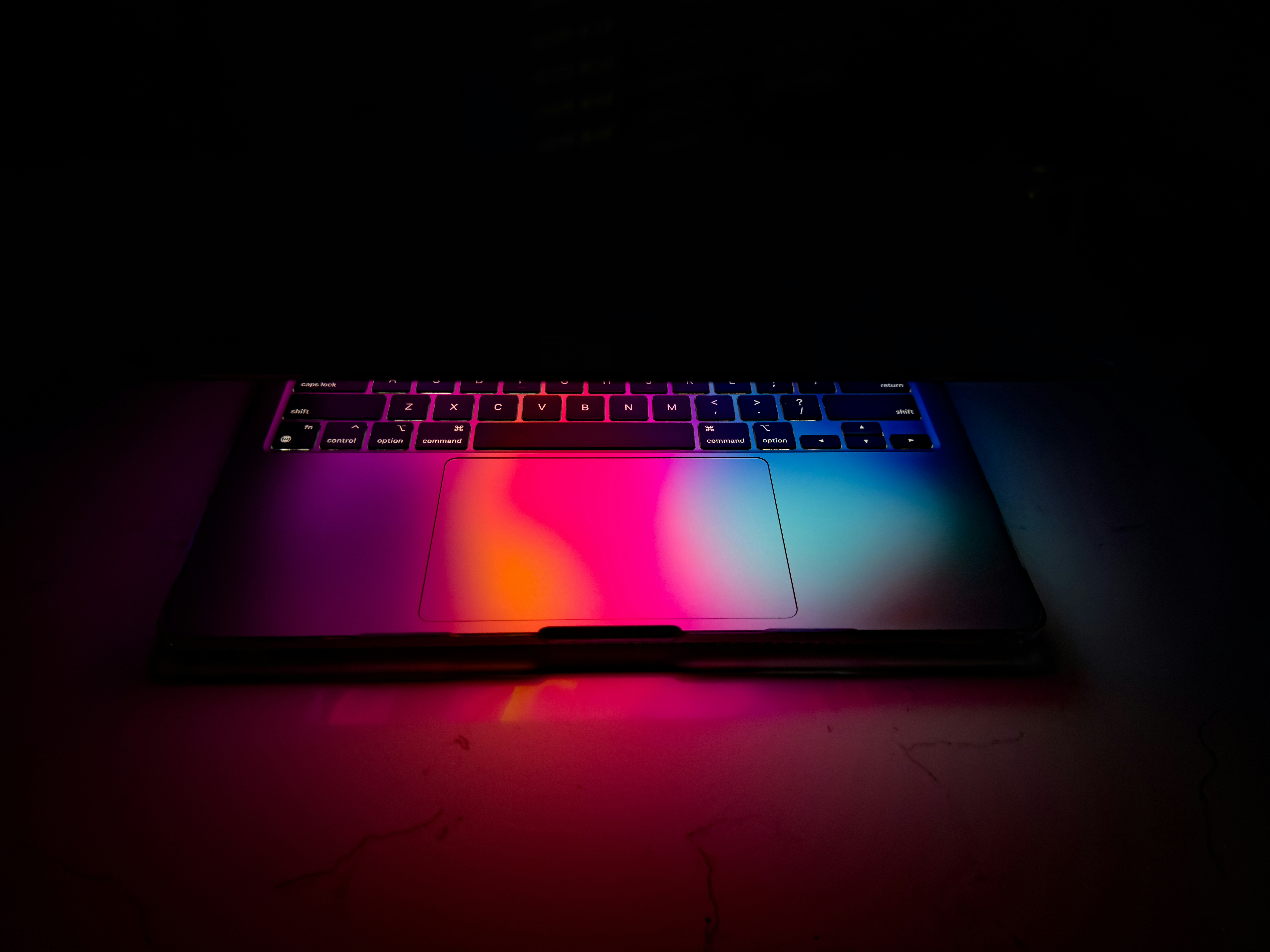 a laptop with a colorful keyboard lit up in the dark, 