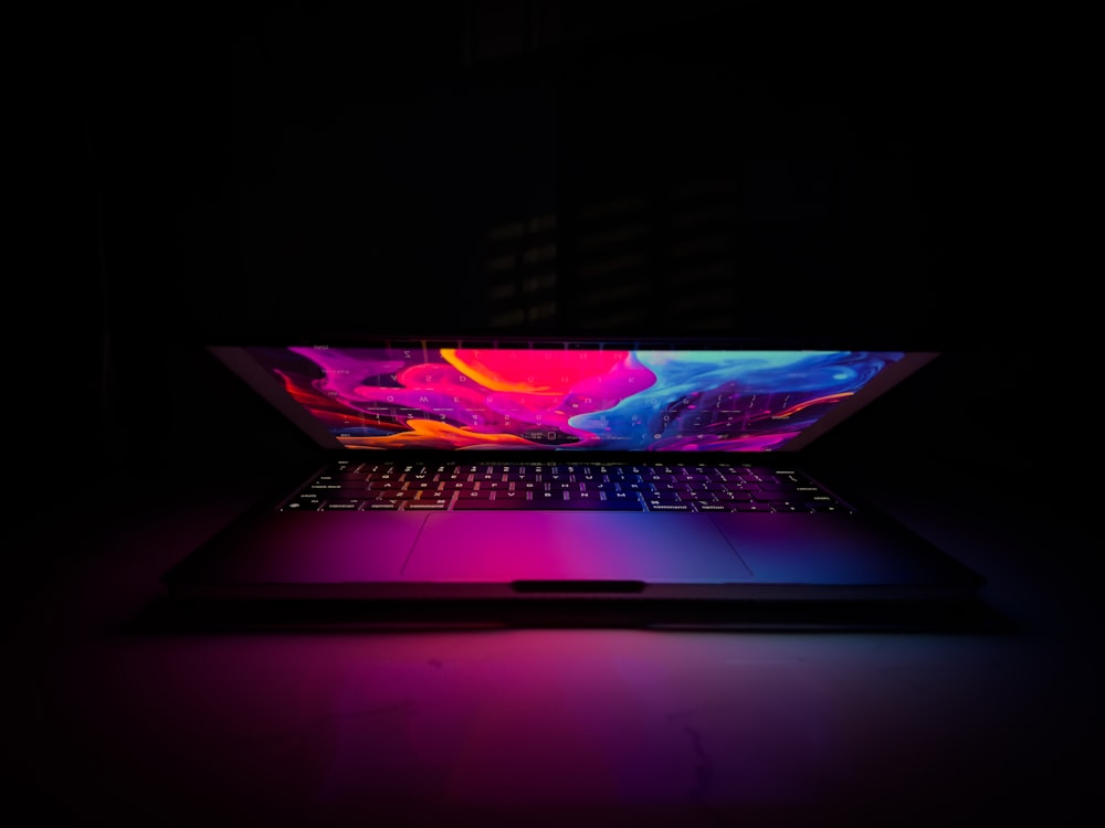 a laptop in the dark with a colorful screen