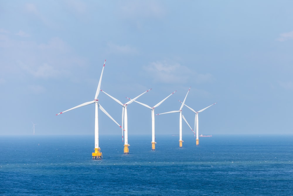 a row of wind turbines in the middle of the ocean