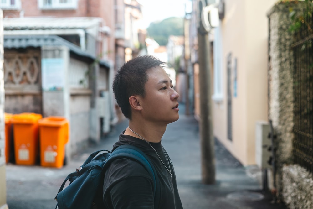 a man with a backpack standing on a narrow street