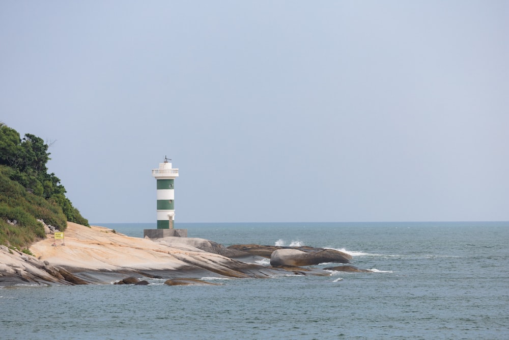 a white and green light house sitting on top of a cliff